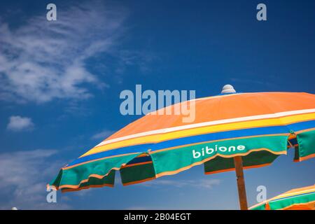 Sonnenschirmstrand zum Entspannen und Sonnenbaden gegen blauen Himmel. Bibione, Italien Stockfoto