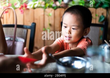 Chinesisches Kind erhält rote Tasche auf dem Esstisch Stockfoto