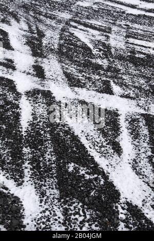 Reifenspuren auf verschneiten Basaltstraßen in Island Stockfoto