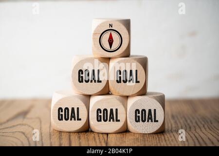 Viele Würfel mit dem Wort Ziel und einem Kompasssymbol auf Holzhintergrund Stockfoto
