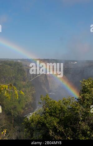 Blick von Sambia auf die Victoria Falls Bridge zwischen Sambia und Simbabwe mit Regenbogen im Sprühbild der Stürze. Stockfoto