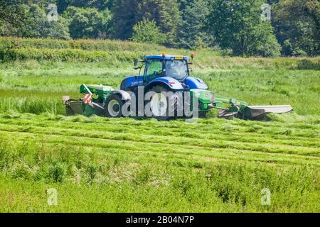 Farmer, der Traktor fährt, der Gras für Silage in Cheshire Farmland England UK schneidet Stockfoto