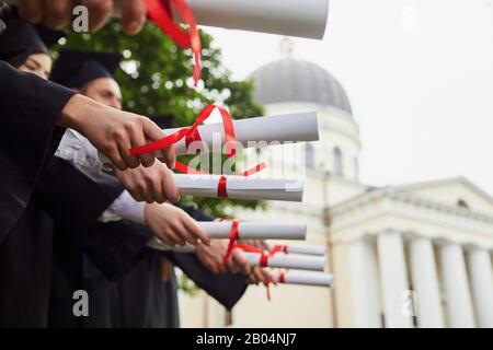 Scrollt Diplome in den Händen einer Gruppe von Absolventen. Stockfoto