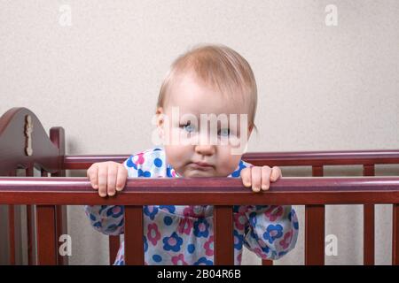Trauriges Babymädchen mit blauen Augen in einer Krippe Stockfoto