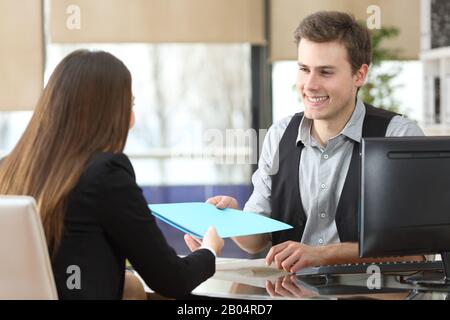 Ein Geschäftsmann, der einem Kunden, der während eines Interviews im Büro sitzt, Dokumente gibt Stockfoto