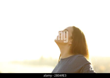 Zufriedene Frau, die bei Sonnenuntergang frische Luft atmet Stockfoto