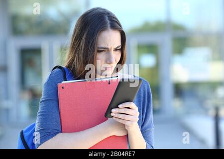 Traurige Studentin überprüft Smartphone und beklagt sich über schlechte Nachrichten auf dem Univeristy-Campus Stockfoto