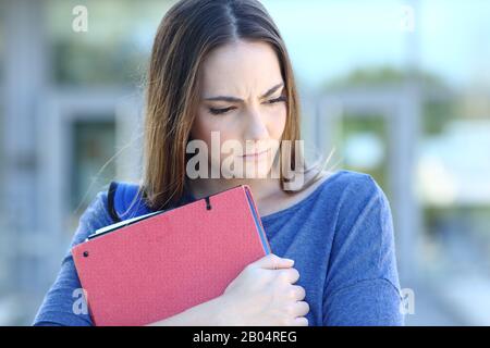 Frontansicht Porträt eines traurigen Studenten, der umarmende Ordner in einer Hochschule umsieht Stockfoto