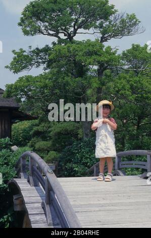 Ein japanisches Mädchen auf einer Brücke im japanischen Korakuen-Garten in Okayama in Japan. Stockfoto