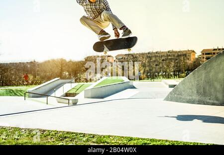 Junger Skater, der Freestyle-Tricks im Stadtpark ausführt - Trendiger Kerl springt mit Skateboard im Freien - Extreme Sportkonzept - Fokus auf Mensch, Schuhe, Brett Stockfoto