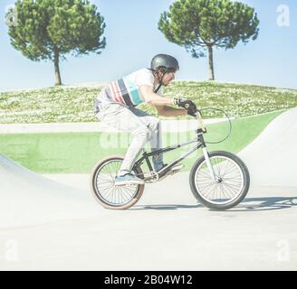 BMX-Biker machen sich bereit für den Sprung im Skatepark im Freien - Junger trendiger Mann, der mit einem speziellen Fahrrad Fähigkeiten und Tricks ausführt - Extreme Sport Co Stockfoto
