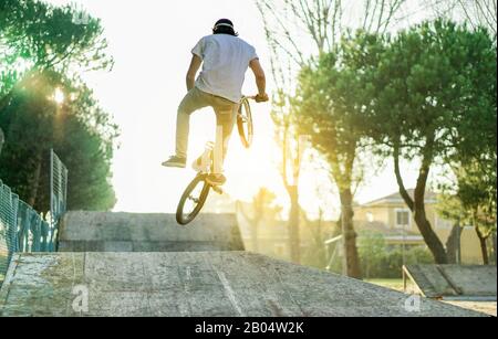 Biker springen im bmx pro Jump Session im Stadtpark mit Gegenlicht - Junger Mann, der bei Sonnenuntergang Extremsport macht - Konzept Für Gefahrenaktivität Stockfoto