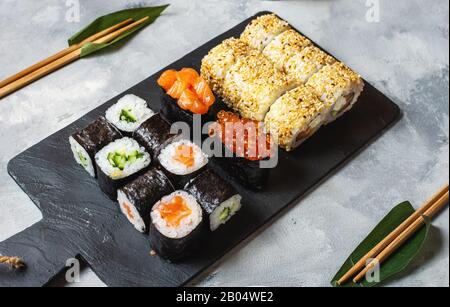 Verschiedene Arten von Sushi am konkreten Hintergrund serviert. Stockfoto