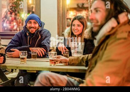 Fröhliche reiche Freunde, die am Abend im Chalet-Pub-Restaurant in den Bergen Bier toben - Junge Leute, die im Winterurlaub Spaß haben - Friendship Konz Stockfoto