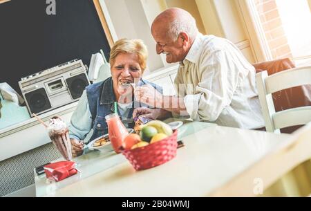 Fröhliches älteres Paar frühstückt morgens im Vintage-Bar-Restaurant - Fröhliches älteres, liebes und gesundes Lifestyle-Konzept - Hauptaugenmerk Stockfoto