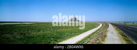 Straße, die durch eine Landschaft führt, der "Mont-Saint-Michel", Normandie, Frankreich Stockfoto