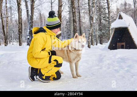 Junge Frau kommuniziert mit einem Husky-Hund im Winterwald Stockfoto