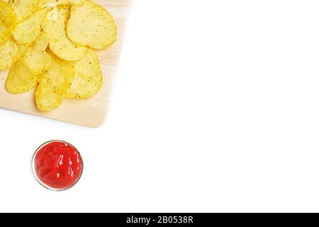 Späne auf einem Holztablett neben Tomatenketchup in einer Schüssel mit Kopierraum. Draufsicht. Nahaufnahme. Stockfoto