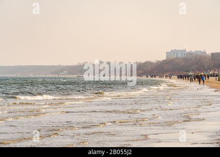 Polen, Sopot, 9. Februar 2020. Menschen am Strand in Sopot. Menge im Winter am Strand. Genießen Sie den Tag im sonnigen Winter in der Nähe des Meeres. Menschen, die hier spazieren gehen Stockfoto