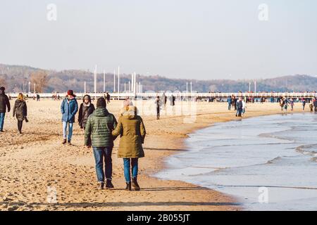Polen, Sopot, 9. Februar 2020. Leute, die am Strand joggen. Nordic Walking. Wintersaison am Meer. Winterspaziergang am Strand. Menschen kühlen sich in Kälte ab Stockfoto