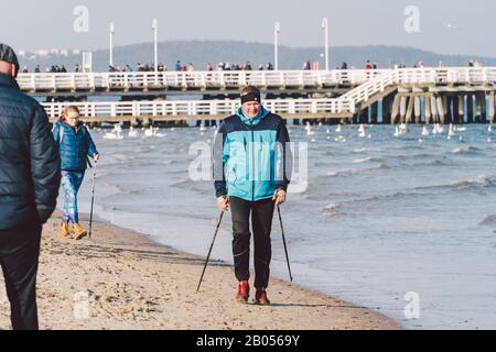 Polen, Sopot, 9. Februar 2020. Menschen am Strand in Sopot. Menge im Winter am Strand. Genießen Sie den Tag im sonnigen Winter in der Nähe des Meeres. Menschen, die hier spazieren gehen Stockfoto
