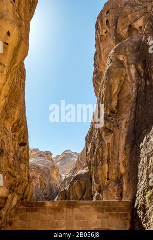 Atemberaubende natürliche Schlucht namens Al-Siq, in den roten Klippen am Wasserfluss gehauen, Petra uralter Stadtkomplex und Touristenattraktion, Haschemite Königreich Jordanien. Sonniger Wintertag, wolkenloser Himmel Stockfoto