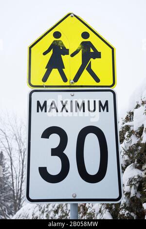 Schilder für Schulkinder, die auf einem Wegweiser, Provinz Quebec, Kanada, kreuzen und Geschwindigkeitsbegrenzungen versehen sind. Stockfoto