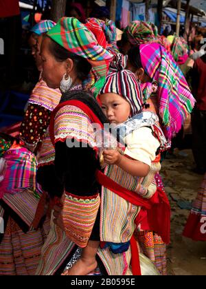Blume Hmong Frau mit Baby auf dem Rücken, Bac ha Sonntag Markt, Lao Cai Provinz, Vietnam Stockfoto
