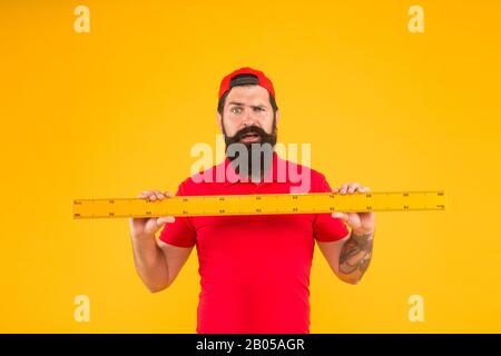 Shop-Assistent. Perfekte Größe. Bärtiger Mann mit großem Messgerät. Messen mit Lineal. Größenmessung. Länge messen. Größe der Kleidung. Studium der Stammdisziplinen. Linealwerkzeuge. Stockfoto