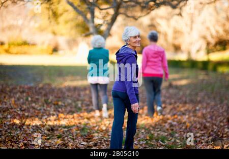Porträt einer lächelnden Seniorin, die mit ihren beiden Freunden in einem Park spazieren ging. Stockfoto