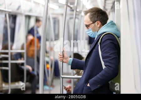 Erschöpfter Mann in Brillen, die sich krank fühlen, Schutzmaske gegen übertragbare Infektionskrankheiten tragen und als Schutz gegen Coronavirus dienen Stockfoto