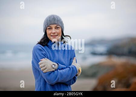 Portrait einer jungen Frau warme Kleidung tragen, während am Strand im Winter. Stockfoto