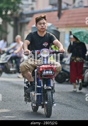 Ein chinesischer junger Mann, der ein Motorroller-Motorrad in der Altstadt von Shanghai, Penglai Road, Huangpu fährt. China Stockfoto