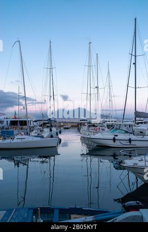 Schöner Naples Yacht-Pier an einem warmen Aprilabend in Kampanien, Italien. Bootsparkplätze im Golf der Stadt. In der Ferne - der Vesuv. Blaue Stunde. T Stockfoto