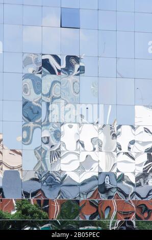 Detail des reflektierend verglasten Gebäudes, in dem die umgebenden Konstruktionen reflektiert und verformt werden. Ungewöhnlicher Blick auf die Straße in Puerto Madero, Buenos Aire Stockfoto