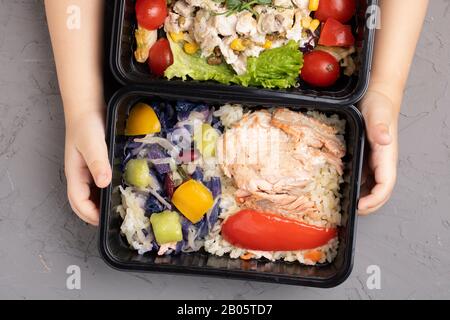 Kinder halten Mittagskästen mit Essen bereit, um zur Schule zu gehen, flaches Lay, Ernährungskonzept Stockfoto