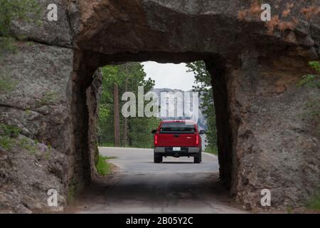 Keystone, SOUTH DAKOTA - 27. Juni 2014: Ein roter Lastwagen fährt durch den Scovel Johnson-Tunnel an der Iron Mountain Road mit Blick auf Mount Rushmore in Keyston Stockfoto