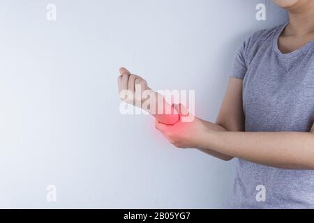 Die Frau in der Nähe hält ihre Handgelenkschmerzen auf weißem Hintergrund mit rotem Fleck. Gesundheitswesen und medizinisches Konzept. Stockfoto