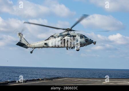 Philippinisches MEER (Feb. 4, 2020) Ein MH-60S Seahawk-Hubschrauber mit den "Island Knights" der Helicopter Sea Combat Squadron (HSC) 25 Caring Marines mit der 31st Marine Expeditionary Unit (MEU) Maritime Raid Force nähert sich dem Docklandungsschiff USS Germantown (LSD 42) der Whidbey-Island-Klasse bei einem vollständigen Besuch des Missionsprofils an Bord, Suchen und Festmachen (VBSS). VBSS verfügt über Kampffähige aus Luft, Boden und Oberflächen aus dem gesamten Blau-Grün-Team, um gegnerischen Schiffen auf See schnell zu verdirden. Germantown, Teil der America Expeditionary Strike Group, 31. MEU-Team, ist im 7. F der USA tätig Stockfoto