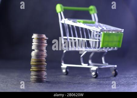 Münzstapel und Warenkorb auf dem Tisch Stockfoto