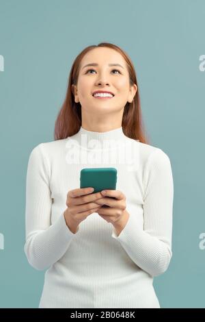 Schöne fröhliche junge Frau legere Kleidung stehen über violette Hintergrund isoliert, mit Handy Stockfoto