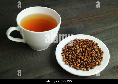 Platte aus Geröstetem Barley mit einer Tasse heißen japanischen Barley Tea oder Mugicha auf Holztisch Stockfoto