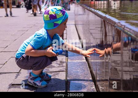 New York, NY 02. Juli 2018: Ein kleiner Junge berührt eine nasse Granitwand eines Brunnens in der Nähe des Eingangs zum Metropolitan Museum. Stockfoto