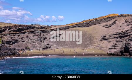 Menschen am Strand von Papakōlea - ein grüner Strand in der Nähe von South Point, einem von vier grünen Stränden der Welt, Big Island, Hawaii. Stockfoto