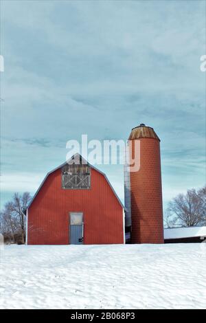 Kansas Red Country Barn mit einem Silo in der Winterzeit mit Schnee im Land. Stockfoto