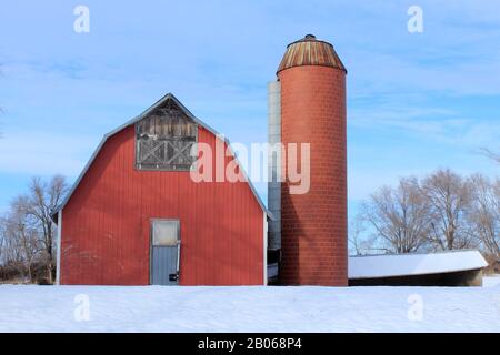 Kansas Red Country Barn mit einem Silo in der Winterzeit mit Schnee im Land. Stockfoto