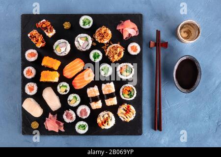 Großes Sushi-Set, von oben mit Sake, Sojasoße und Essstäbchen aufgenommen. Eine Auswahl an verschiedenen Maki, Nigiri und Brötchen Stockfoto