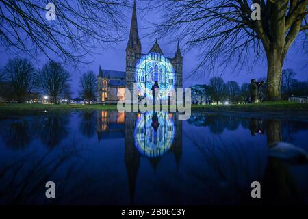 Die Menschen sehen, wie Lichtprojektionen die Westfront der Kathedrale von Salisbury bedecken, wo eine Licht- und Tonkunst-Installation mit dem Titel Sarum Lights das 800-jährige Jubiläum der Kathedrale im Jahr 2020 markiert, indem sie die Innen- und Außenbeleuchtung zusammen mit Musik beleuchten. Stockfoto