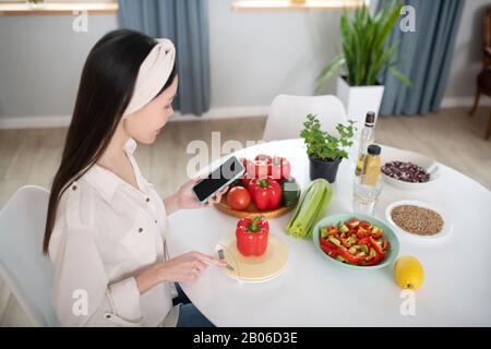 Junge Frau mit Smartphone mit rotem Pfeffer. Stockfoto