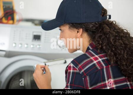 Weibliche Arbeitskraft, die den Status einer Waschmaschine überprüft Stockfoto